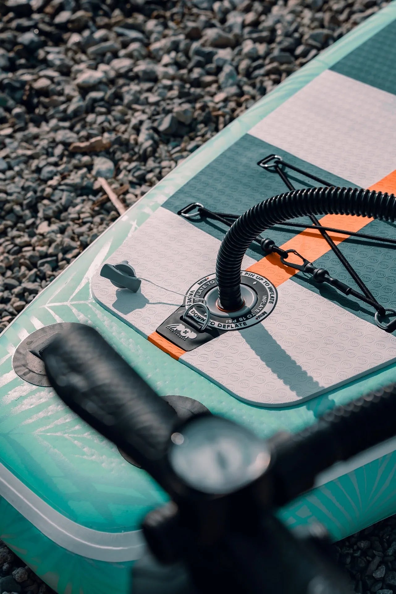 Close-up of the inflation valve on the 11'0" Yacht Hopper inflatable paddleboard, showing the connected black pump hose and pressure gauge in the foreground
