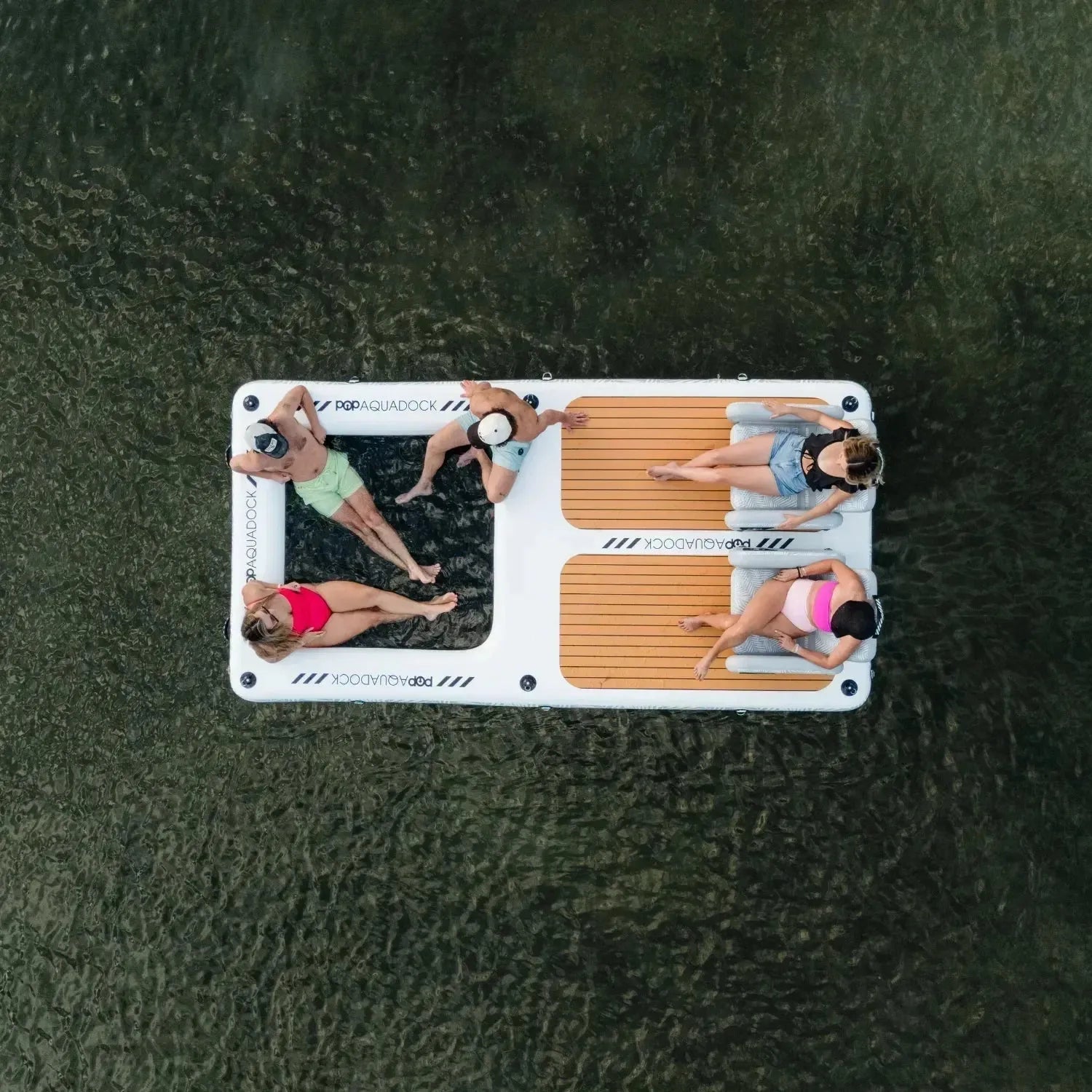 Overhead view of four friends relaxing on a POP Aquadock inflatable floating platform, enjoying time together on the water.