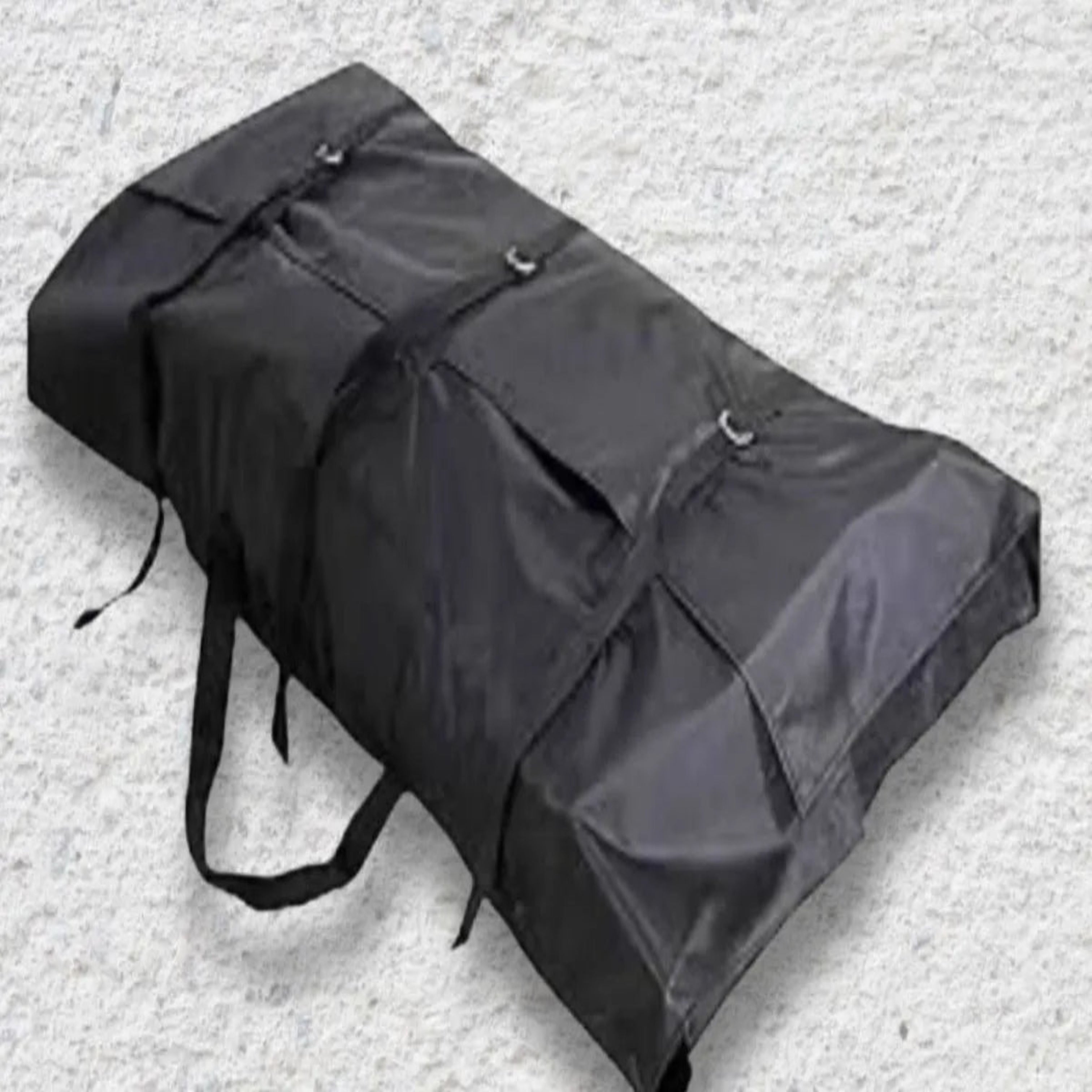 Black carrying bag with straps on a gray surface